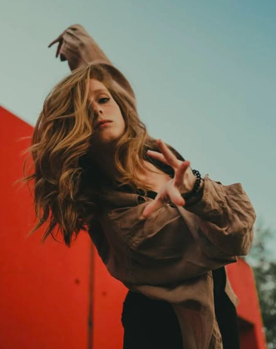 Charlène, danseuse contemporaine, capturée en mouvement expressif devant un mur rouge, incarnant l’énergie du lyrical flow.